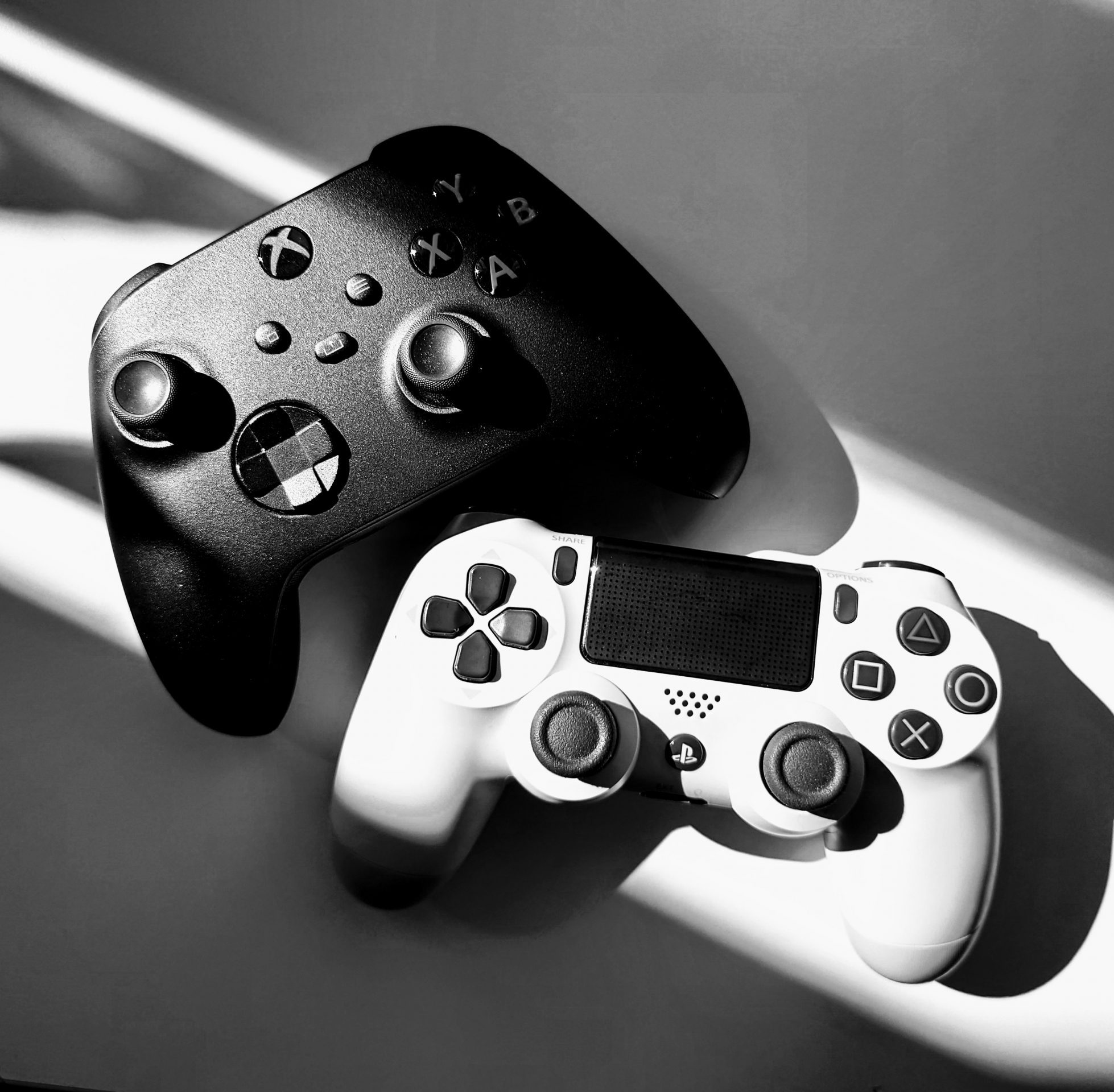 Videospiel.kultur. Zu sehen sind ein XBox Controller in schwarz und ein Playstation 4 Controller in weiß. Medienpädagogik